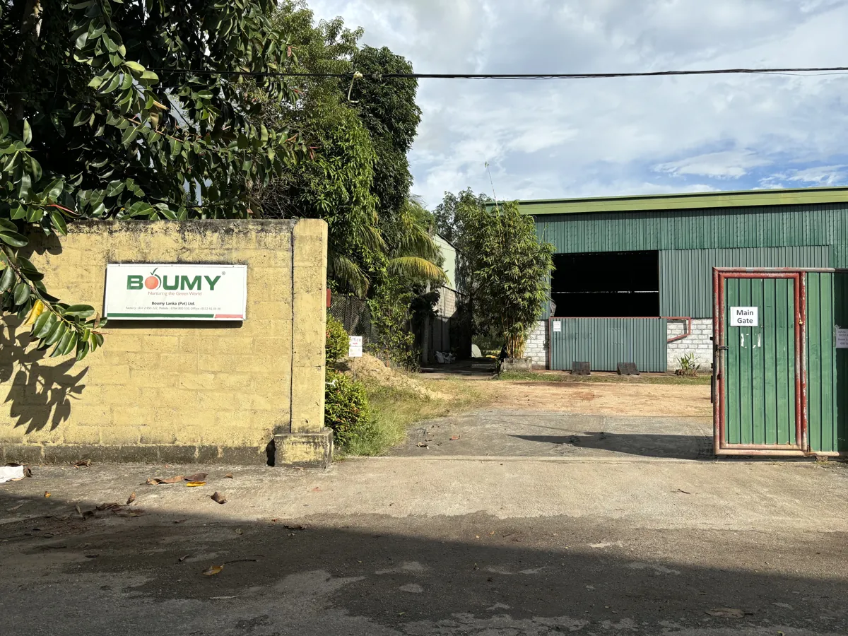 Boumy Lanka factory entrance and green industrial building, with the company sign beside the main gate