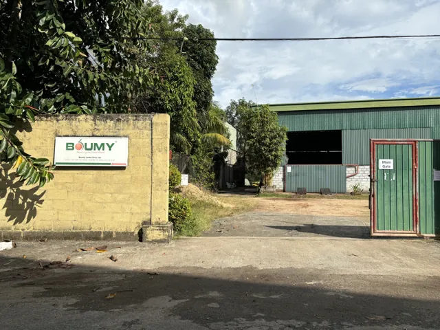 Main gate, Boumy company sign and factory viewed from the access road