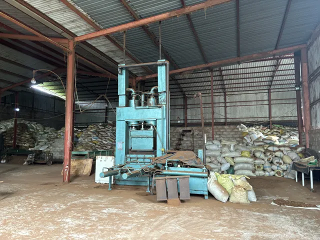 Factory interior showing processing machinery, steel roof structure and stored bags of material